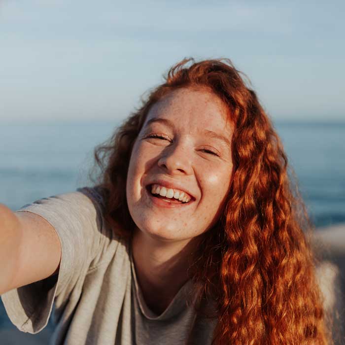 Cheerful young woman taking a selfie next to the sea
