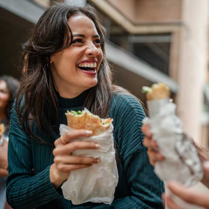 Woman holding a sandwich and laughing